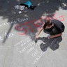 A man writes a message on the pavement in central Manchester, England