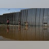 The border structure separating San Diego from Tijuana, Mexico, as people walk along the beach in Tijuana.