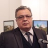 Karlov is shown here speaking at the gallery, as the man who would kill him looms in the background.