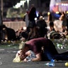A man lays on top of a woman as others flee the Route 91 Harvest country music festival grounds after a shooting in Las Vegas
