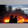 Protesters stand next to fire at the entrance to the Israeli settler outpost of Amona. 