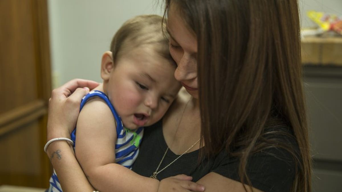 FILE: Mara Mancini, holds her son, Kyson Clark, in the law offices of Saeed and Little LLP in Indianapolis, Ind.