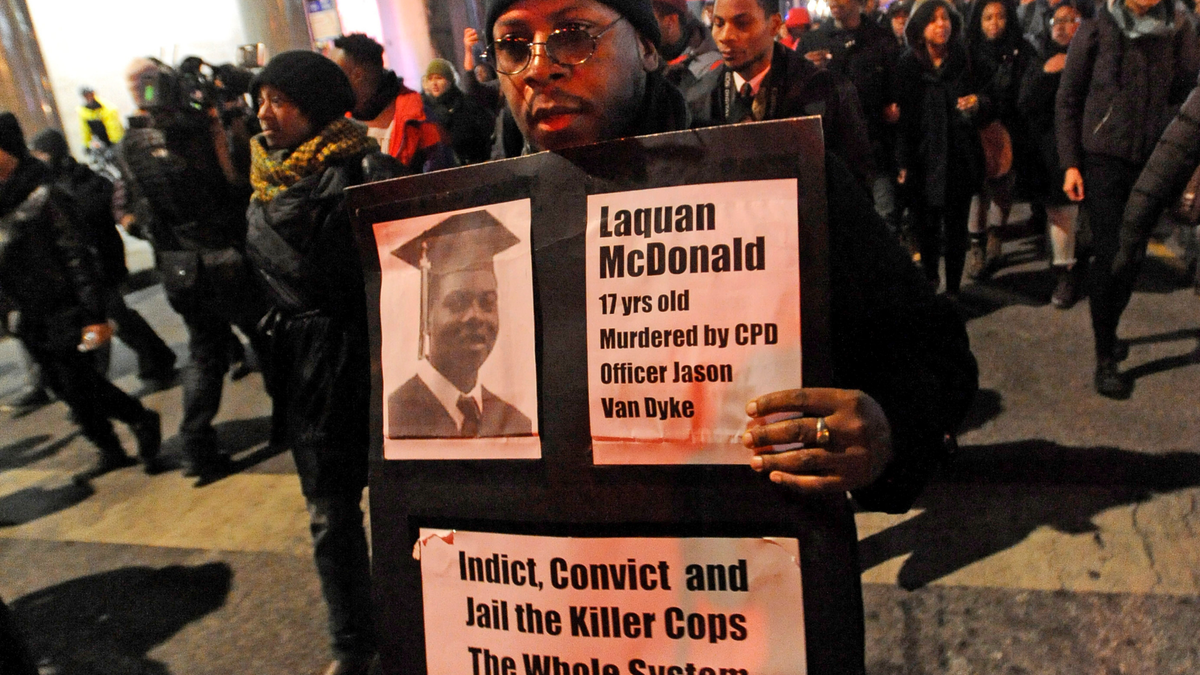 FILE - In this Nov. 24, 2015 file photo, a man holds a sign with a photo of Laquan McDonald on it, during a protest of the police shooting 17-year-old McDonald, in Chicago. The city of Chicago is watching closely for word of a verdict in the case of Chicago police Officer Jason Van Dyke charged with murder in the 2014 shooting of McDonald. The Chicago Police Department has canceled days off and put officers on 12-hour shifts. (AP Photo/Paul Beaty, File)