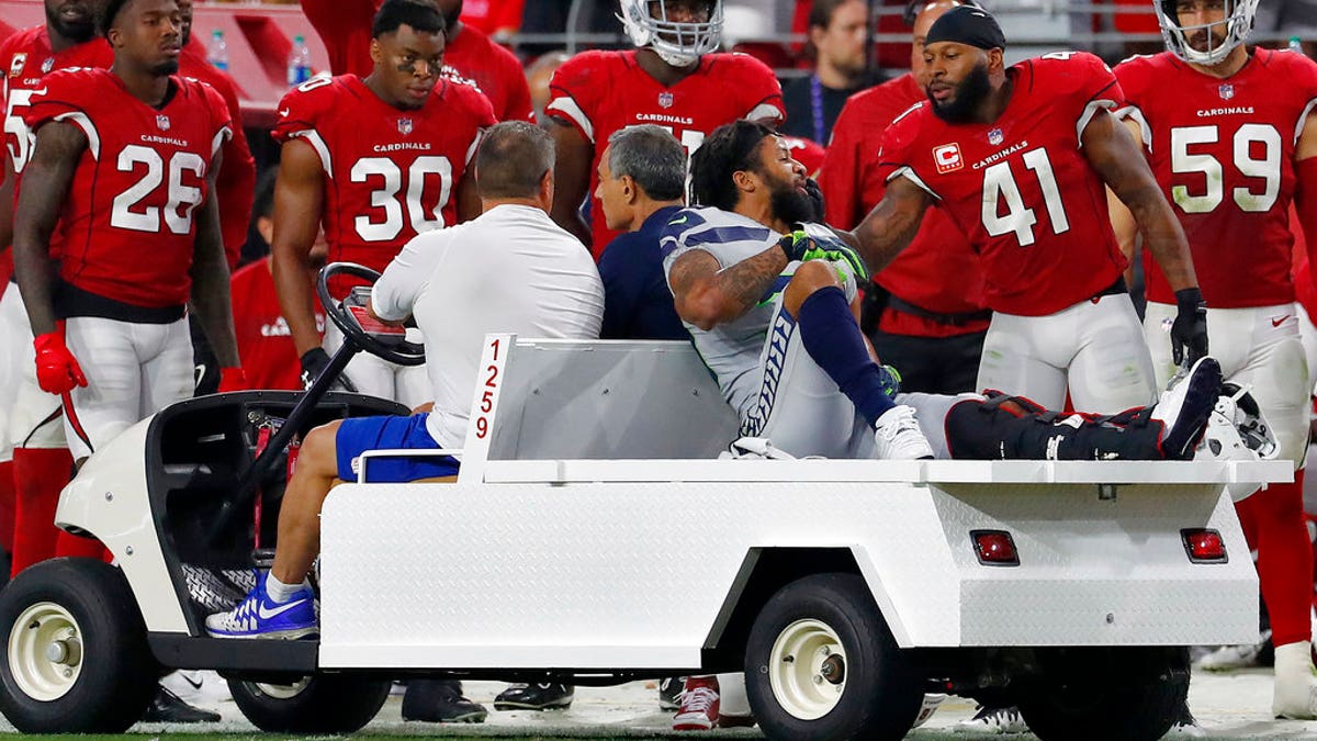 Seattle Seahawks defensive back Earl Thomas is greeted by Arizona Cardinals players as he leaves the field after breaking his leg during the second half of an NFL football game.