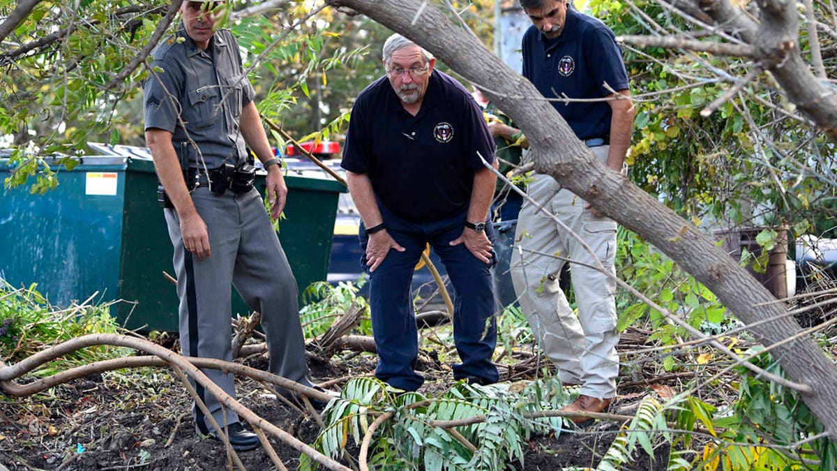 A New York state trooper and members of the National Transportation Safety Board view the scene of Saturday's fatal crash in Schoharie, N.Y.