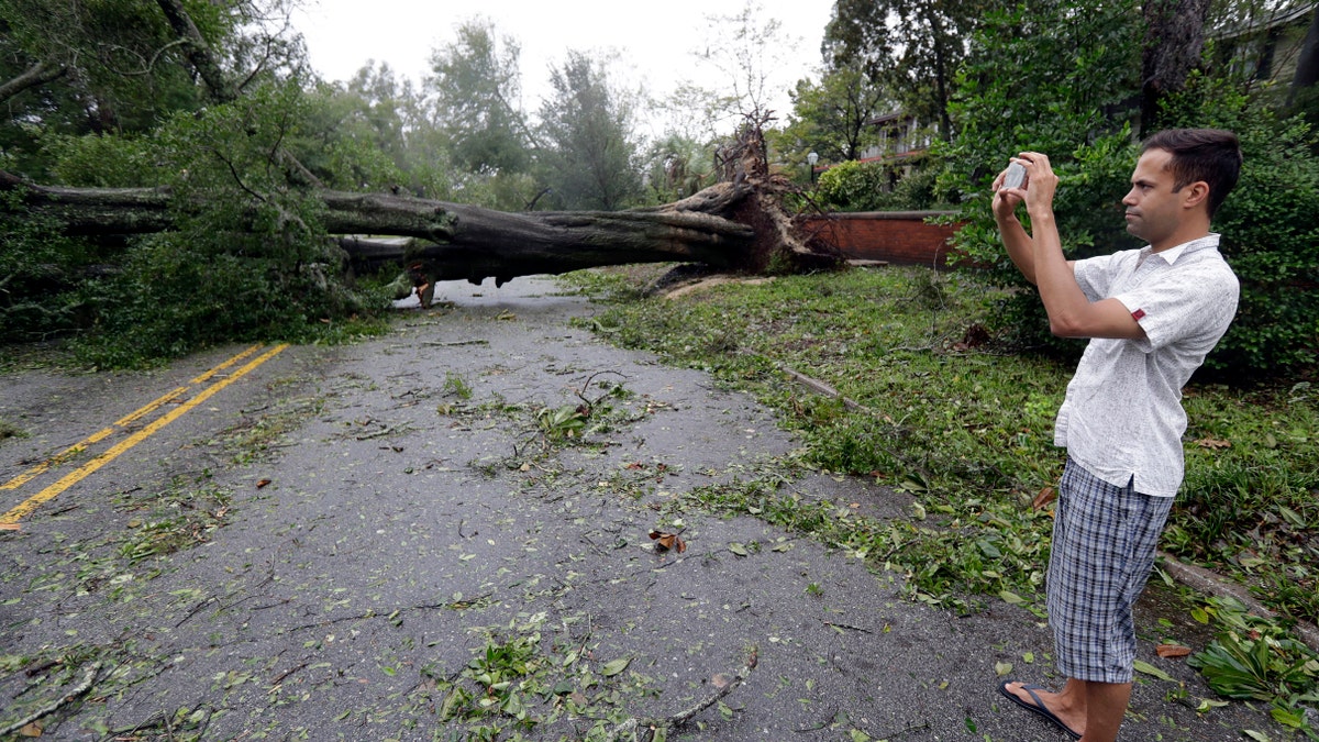 Shane Fernando takes a photo of fallen trees near his home in Wilmington, North Carolina. Fernando is worried about the approach of Hurricane Michael because he sustained tree damage to his house and has tarps covering parts of the exterior.