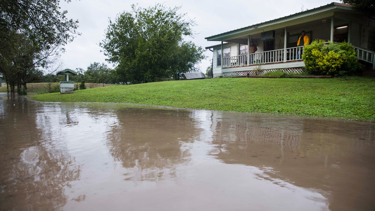 Joe Mercer and his friend Tonya Grace watch weather reports from their porch as the rising waters from the Colorado River floods their property.