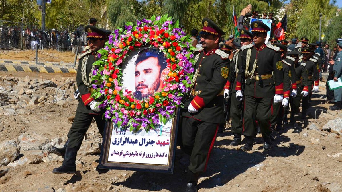 Guards of honor carry a photo of Gen. Abdul Raziq, Kandahar police chief, who was killed by a guard, during his burial ceremony in Kandahar, Afghanistan, Friday, Oct. 19, 2018.