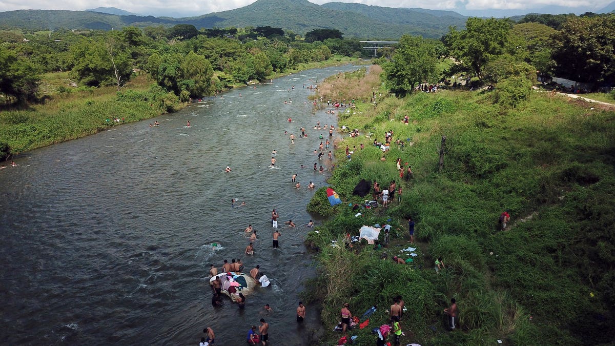 Honduran migrants take a bath in a river in Pijijiapan, Mexico, Thursday, Oct. 25, 2018. Thousands of Central American migrants renewed their hoped-for march to the United States on Wednesday, setting out before dawn with plans to travel another 45 miles (75 kilometers) of the more than 1,000 miles that still lie before them. (AP Photo/Rodrigo Abd)