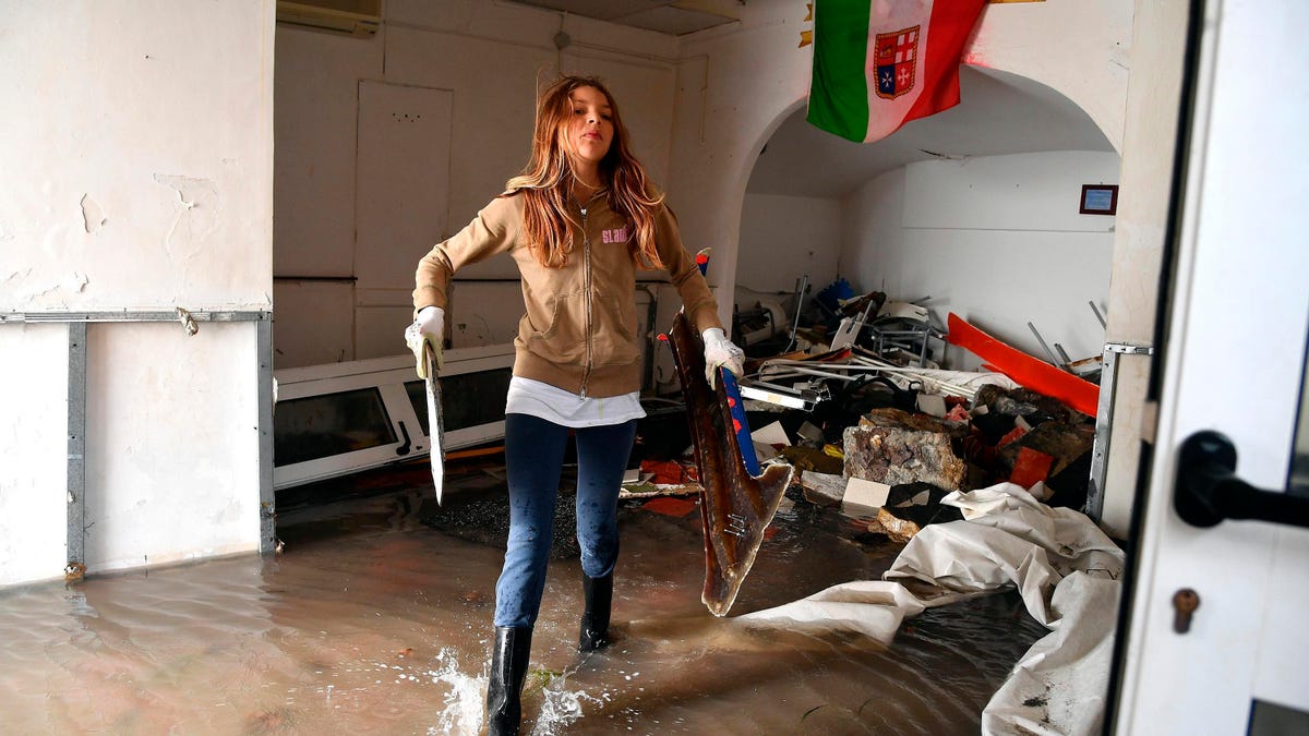 A woman cleans up debris from a flooded room a day after a storm, in Boccadasse, northern Italy, Tuesday, Oct. 30, 2018. (Luca Zennaro/ANSA via AP)