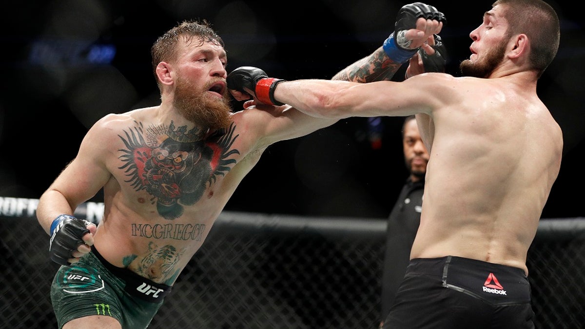 Conor McGregor, left, and Khabib Nurmagomedov throw punches during a lightweight title mixed martial arts bout at UFC 229 in Las Vegas, Saturday, Oct. 6, 2018. (AP Photo/John Locher)