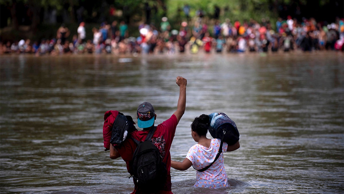 A migrant raised his fist as he neared the Mexican side of the Suchiate River, that connects Guatemala and Mexico. (AP Photo/Santiago Billy)