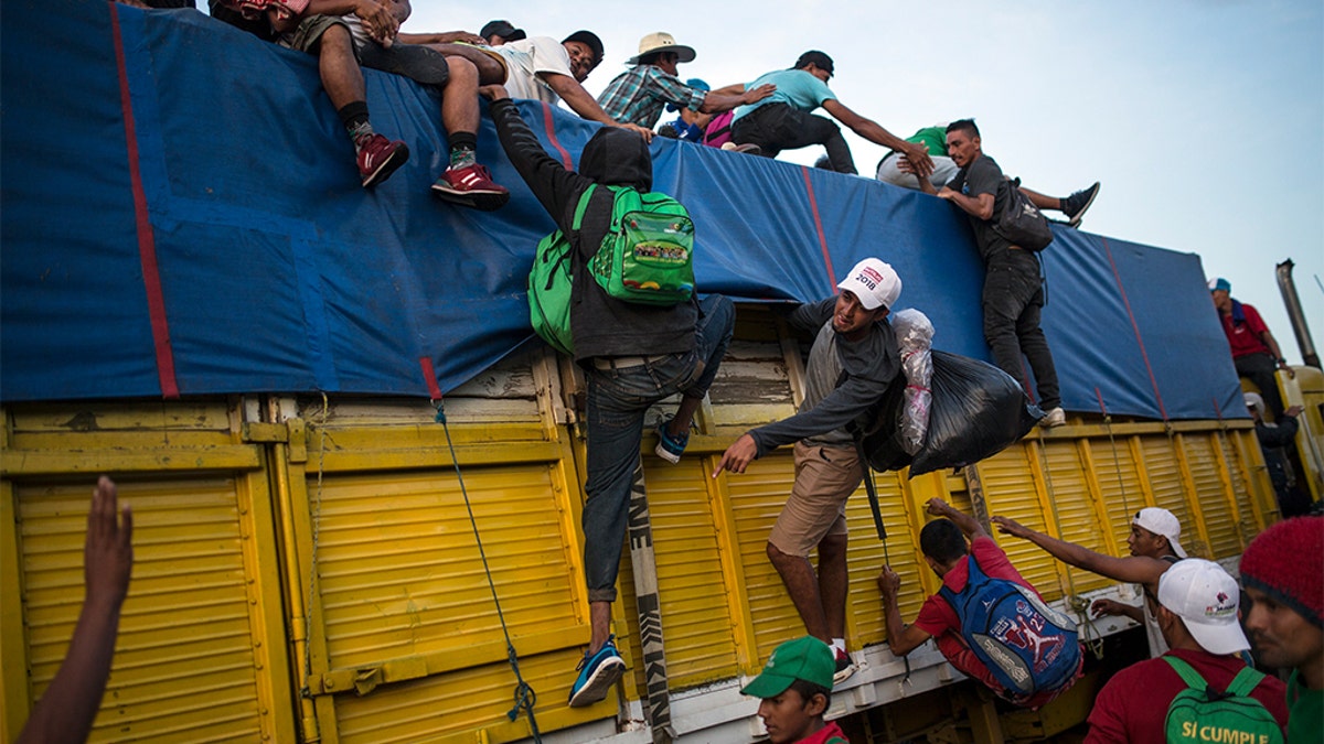 Migrants climbing on a truck to ride on the road that connects Tatanatepec with Niltepec, Mexico. (AP Photo/Rodrigo Abd)