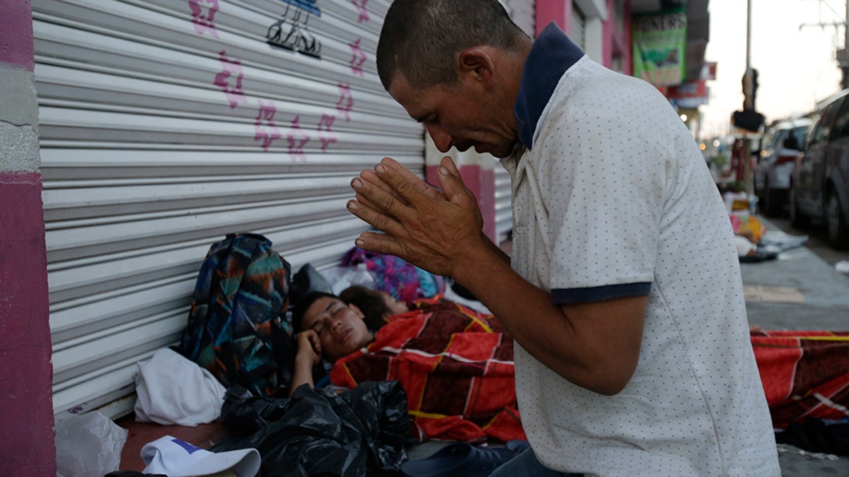 Marvin Sanabria, a Central American migrant traveling with a caravan to the U.S., kneels in prayer after waking up, in Huixtla, Mexico, Tuesday, Oct. 23, 2018. The caravan, estimated to include more than 7,000 people, had advanced but still faced more than 1,000 miles, and likely much further, to the end of the journey. (AP Photo/Moises Castillo)