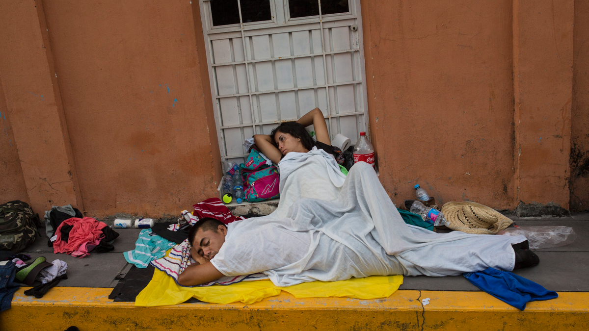 A migrant woman slowly begins to wake after sleeping on a sidewalk in Tapanatepec, Mexico, Sunday, Oct. 28, 2018. Thousands of migrants who are part of a caravan of Central Americans trying to reach the U.S. border took a break Sunday on their long journey toward the U.S. border.
