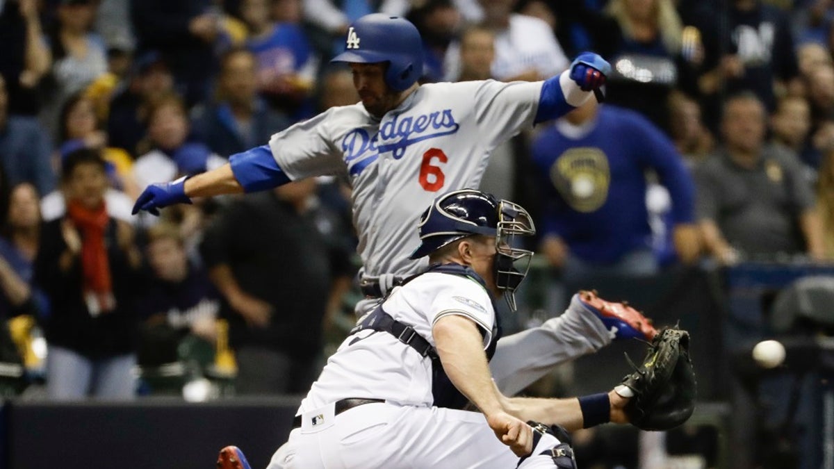 FILE - Los Angeles Dodgers' Brian Dozier scores past Milwaukee Brewers catcher Erik Kratz during the fifth inning of Game 6 of the National League Championship Series baseball game Friday.