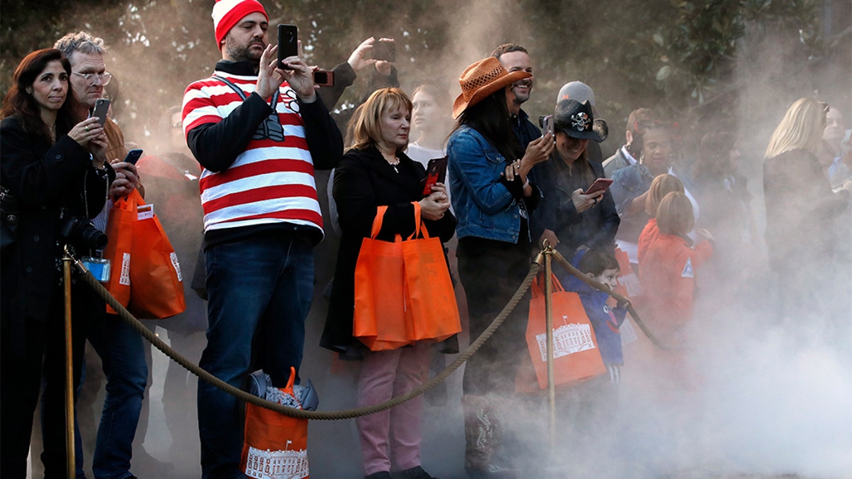 Parents taking photographs of their children in Halloween costumes, as mist from a fog machine rose around them, during a trick-or-treat event with President Donald Trump and first lady Melania Trump at the White House.