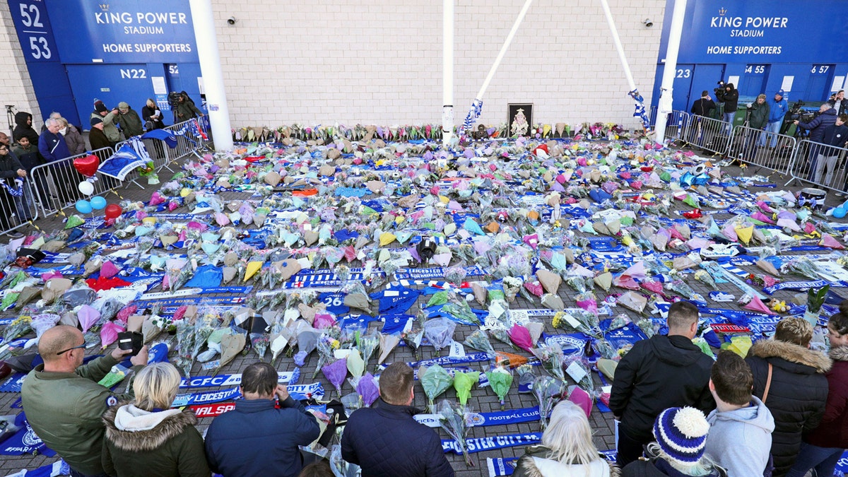 Supporters pay tribute outside Leicester City Football Club after a helicopter crashed in flames the day before, in Leicester, England, Sunday, Oct. 28, 2018. A helicopter belonging to Leicester City's owner, Thai billionaire Vichai Srivaddhanaprabha, crashed in flames in a car park next to the soccer club's stadium shortly after it took off from the field following a Premier League game on Saturday night. (Aaron Chown/PA via AP)