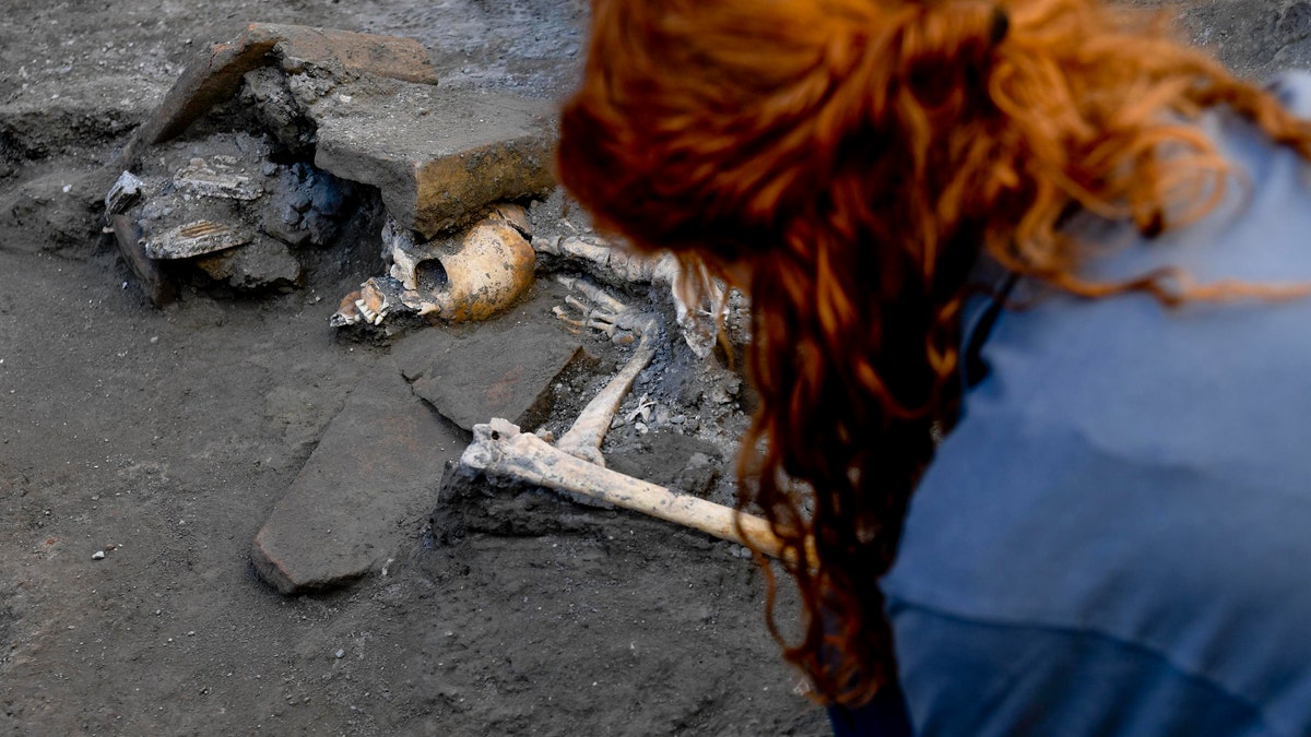 An archaeologist inspects skeletons in the Pompeii archaeological site, Italy, Wednesday, Oct. 24, 2018. (Ciro Fusco/ANSA via AP)
