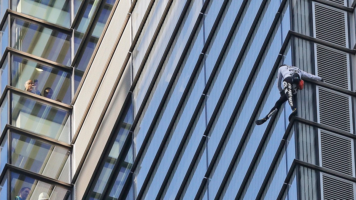 People watch from inside the building as urban climber dubbed the French Spider-Man, Alain Robert scales the outside of Heron Tower building in London