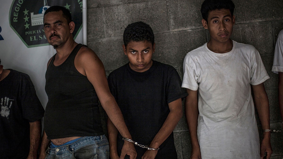 Suspected members of the 18th Street gang stand handcuffed in pairs at a police station in Panchimalco, near San Salvador, El Salvador. The gangs trace their origins to street life in cities such as Los Angeles, where many Salvadorans sought refuge during their country’s 1980-1992 civil war. (AP Photo/Manu Brabo, File)