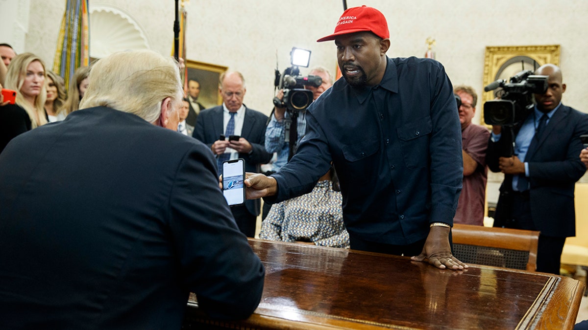 Rapper Kanye West shows President Trump a photograph of a hydrogen plane during a meeting in the Oval Office of the White House, Thursday, Oct. 11, 2018.