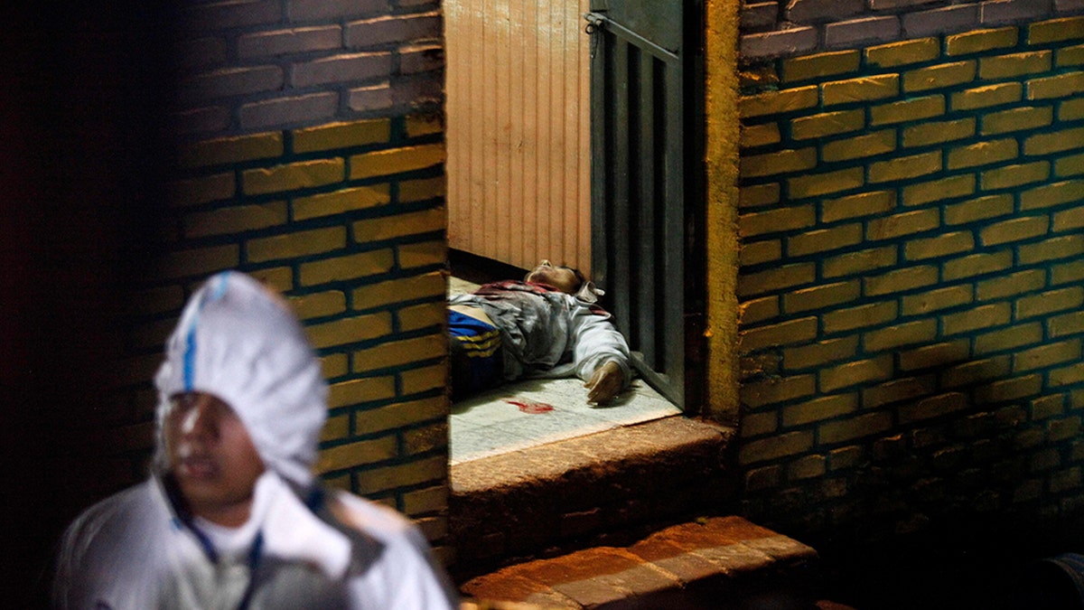 A body is stretched out at the door of a bar in the community of Comayaguela, Honduras, on Friday. At least eight people were killed and two others wounded at the bar that day, police say. (AP Photo/Fernando Antonio)
