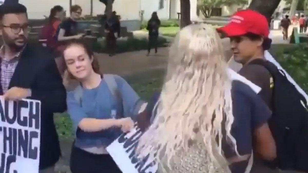 A student rips apart a pro-Kavanaugh sign from the Young Conservatives of Texas at the University of Texas, Austin on Tuesday.