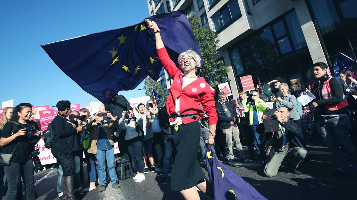 An anti-Brexit campaigner dressed as Theresa May waves European Union flags during the People's Vote March for the Future in London, a march and rally in support of a second EU referendum, in London, Saturday Oct. 20, 2018. Thousands of protesters gathered in central London on Saturday to call for a second referendum on Britain’s exit from the European Union.