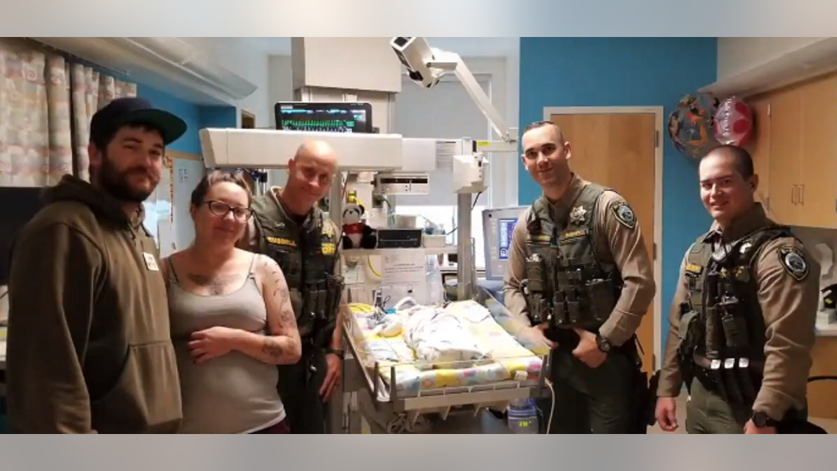 Clackamas County sheriff’s deputies visiting baby Audrey in the hospital after saving her life.