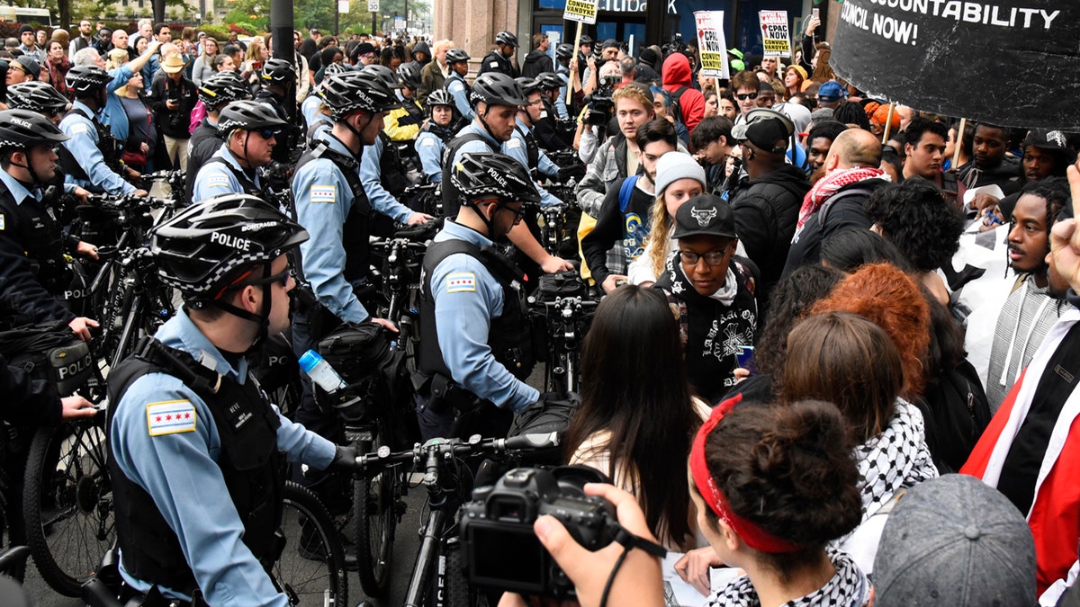 Protesters stand near police in the downtown area after a jury convicted white Chicago police officer Jason Van Dyke of second-degree murder in the 2014 shooting of black teenager Laquan McDonald Friday, Oct. 5, 2018, in Chicago.