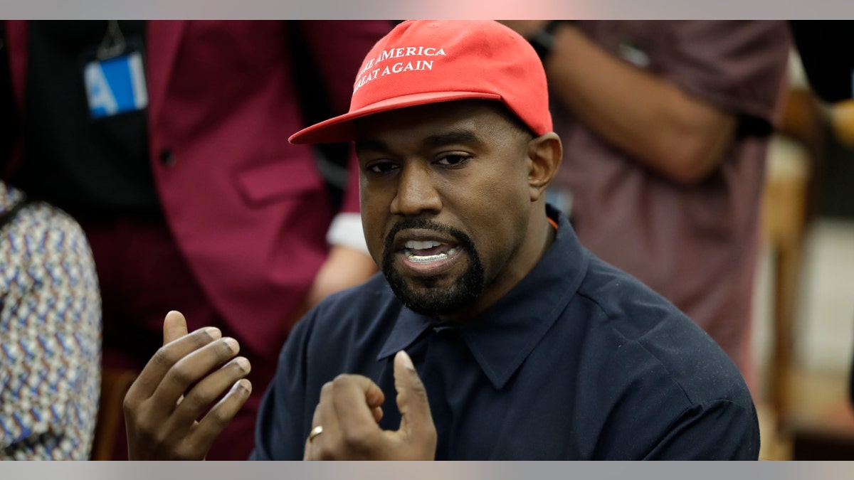 Kanye West, displaying his MAGA hat, talks with President Trump and others at the Oval Office on Thursday.