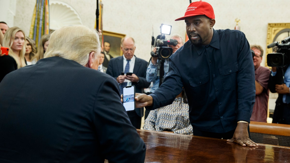 Rapper Kanye West shows President Donald Trump a photograph of a hydrogen plane during a meeting in the Oval Office of the White House, Thursday, Oct. 11, 2018, in Washington.