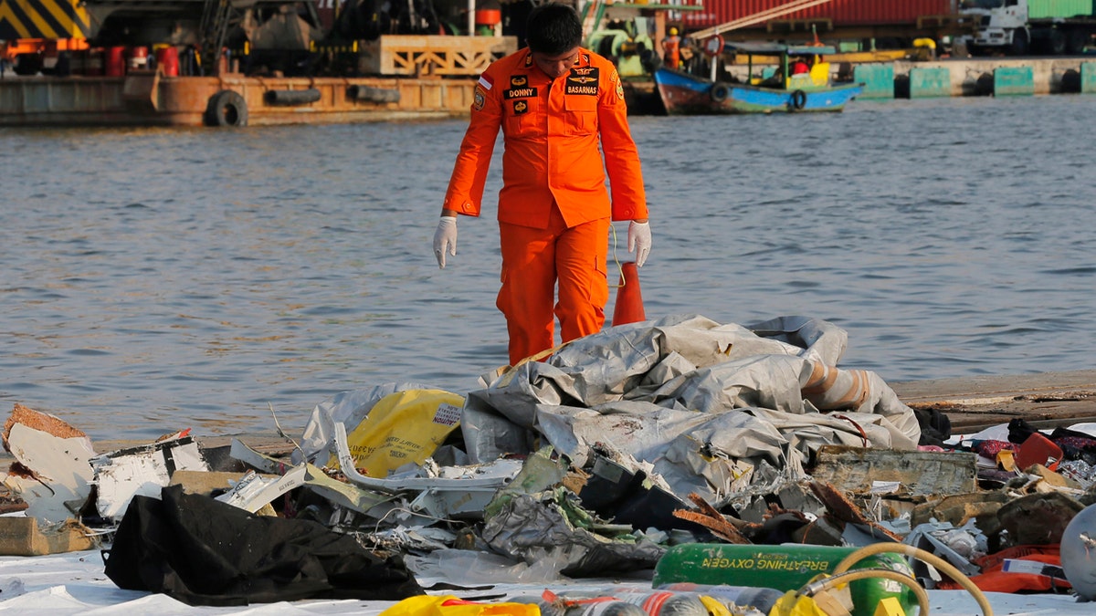 A member of Indonesian Search and Rescue Agency (BASARNAS) inspects debris recovered from near waters where a Lion Air passenger jet crashed off, at Tanjung Priok Port in Jakarta, Indonesia Monday, Oct. 29, 2018.