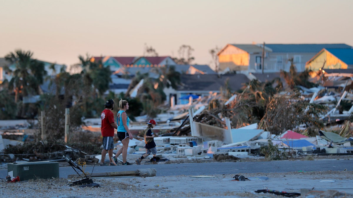 People walk amidst rubble in the aftermath of Hurricane Michael in Mexico Beach, Fla., Saturday, Oct. 13, 2018.
