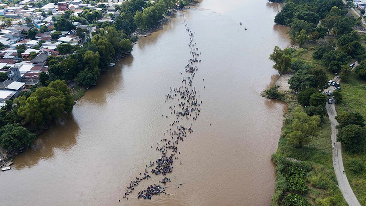 A group of Central American migrants bound for the U.S border wade in mass across the Suchiate River, that connects Guatemala and Mexico, in Tecun Uman, Guatemala.