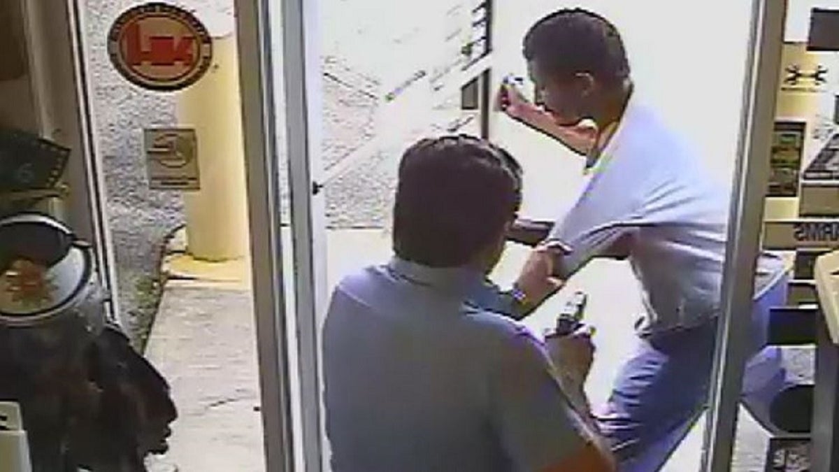 Lakeland Commissioner Michael Dunn holds a gun in his right hand while trying to keep Cristobal Lopez from carrying a hatchet out of his store on Oct. 3.