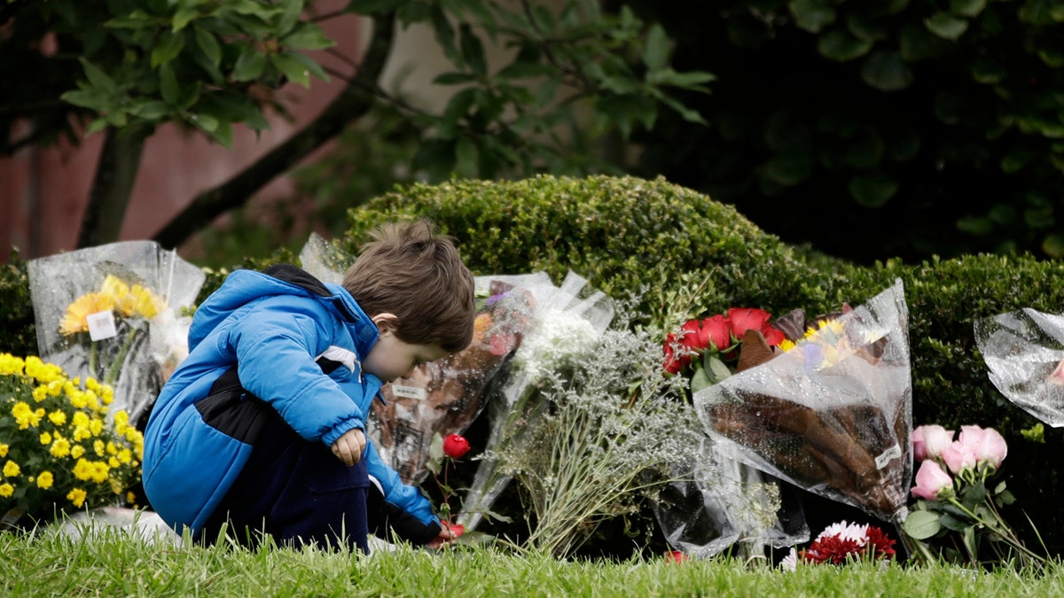 Gideon Murphy places a flower at the Tree of Life Synagogue in Pittsburgh, Sunday, Oct. 28, 2018.