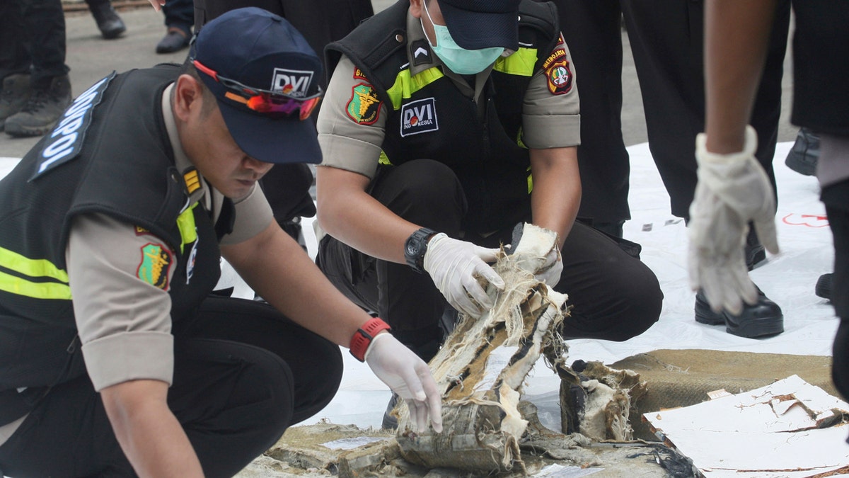 Indonesian forensic team members examine parts of airplane recovered from the area where a Lion Air plane crashed.