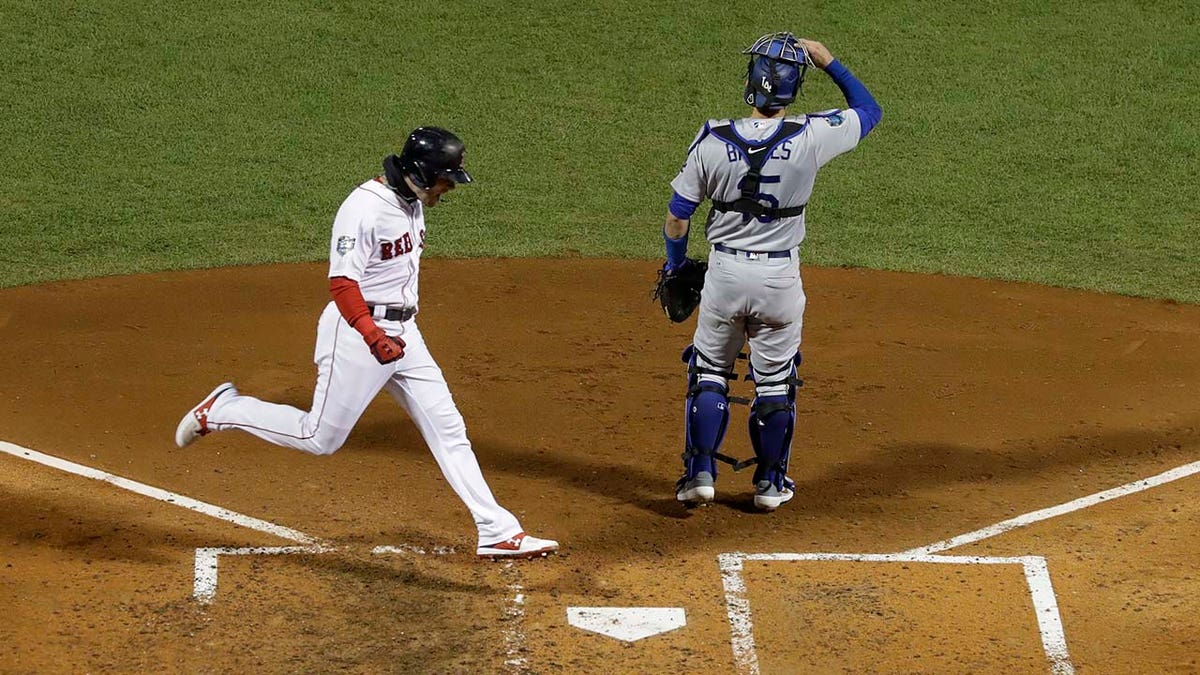 Boston Red Sox's Andrew Benintendi scores past Los Angeles Dodgers catcher Austin Barnes on a hit by J.D. Martinez during the fifth inning of Game 2 of the World Series baseball game Wednesday, Oct. 24, 2018, in Boston. (AP Photo/David J. Phillip)