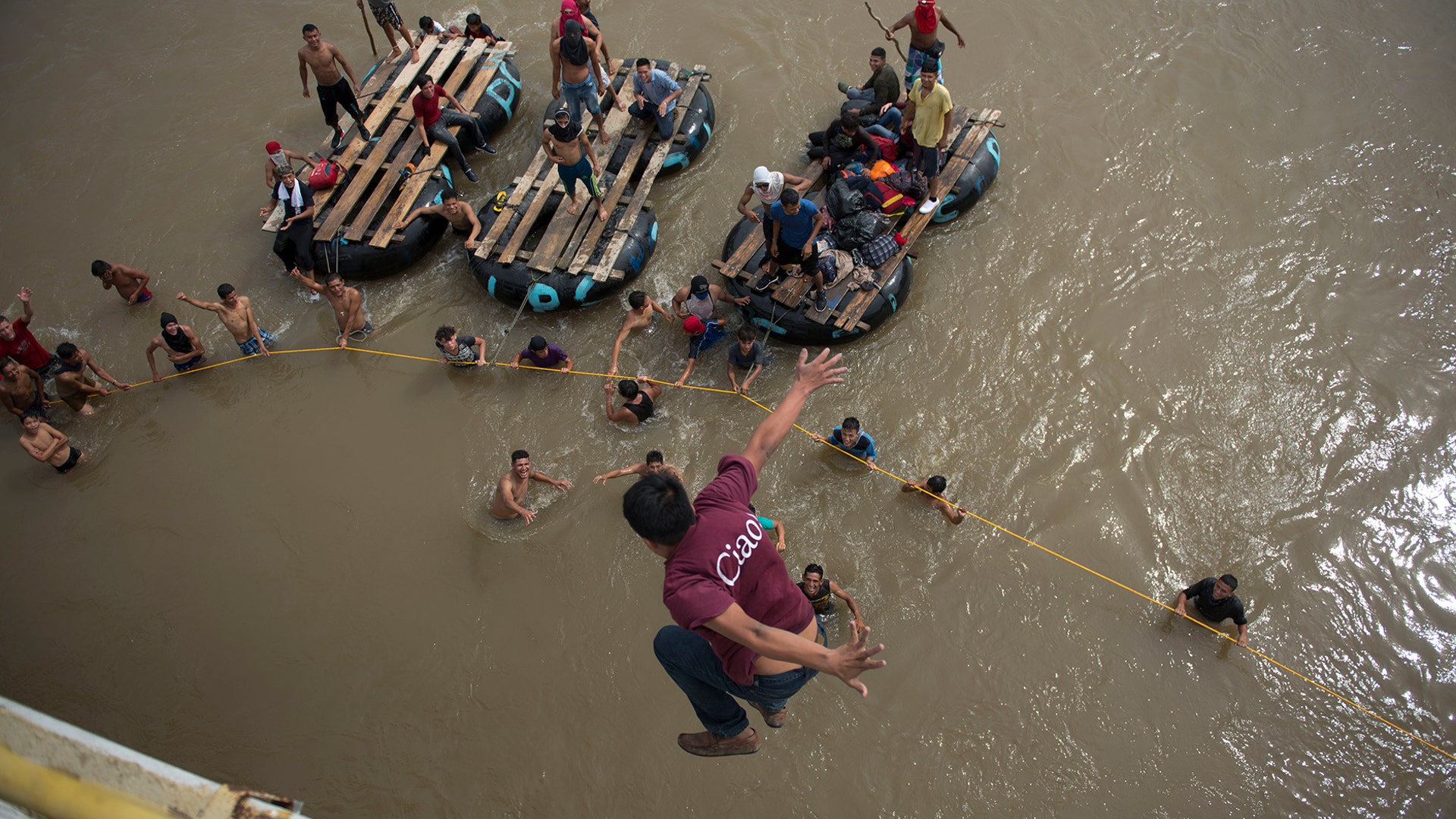 Migrants tired of waiting to cross into Mexico, jump from a border bridge into the Suchiate River, in Tecun Uman, Guatemala, on Oct. 19, 2018. 