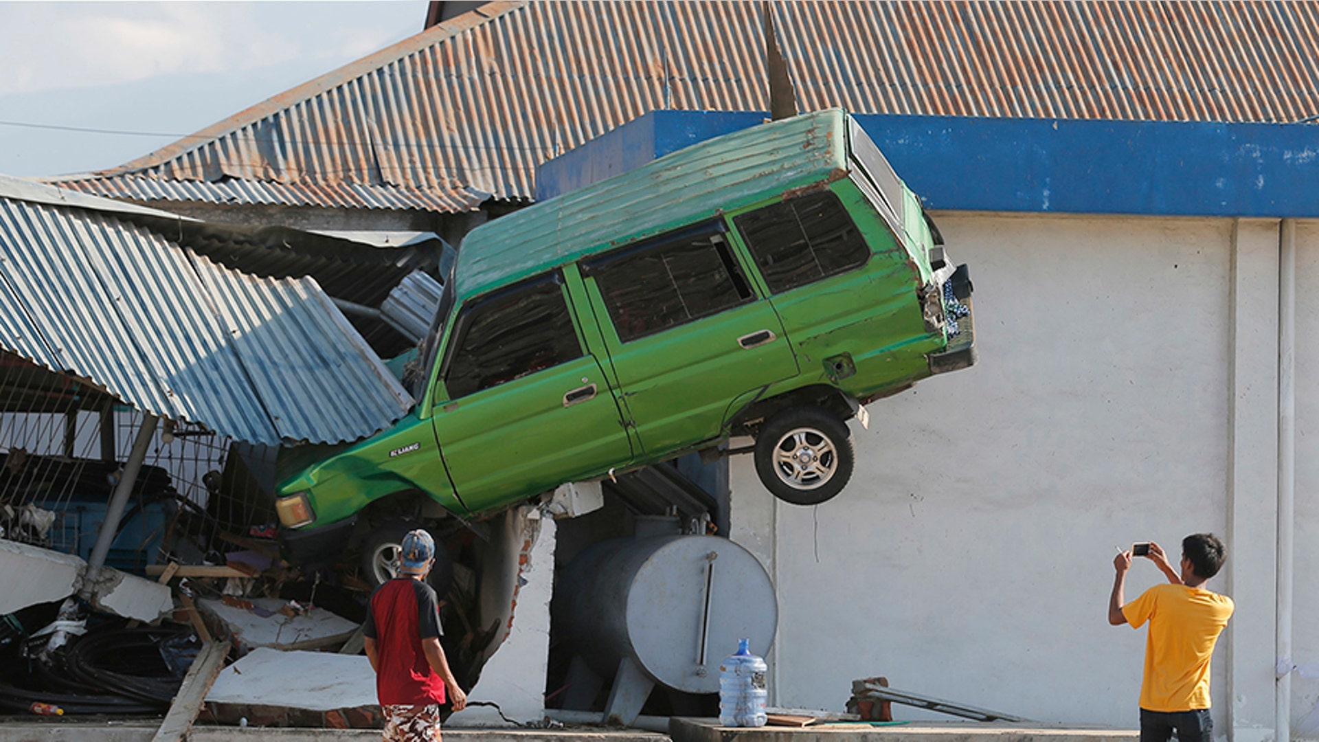 A man takes a photo of a car lifted into the air following a massive earthquake and tsunami at Talise beach in Palu, Central Sulawesi, Indonesia, Oct. 1, 2018.