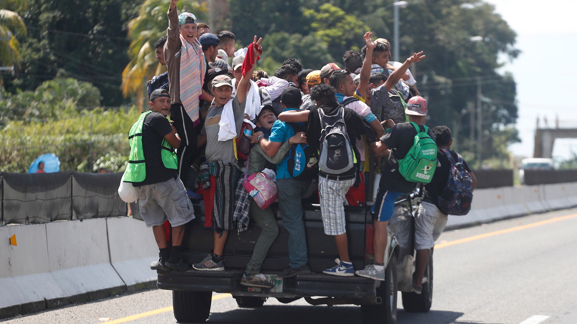 Central American migrants making their way to the United States cling to the side of a truck of river who offered them a free ride as they in arrive Tapachula, Mexico, on Oct. 21, 2018. 