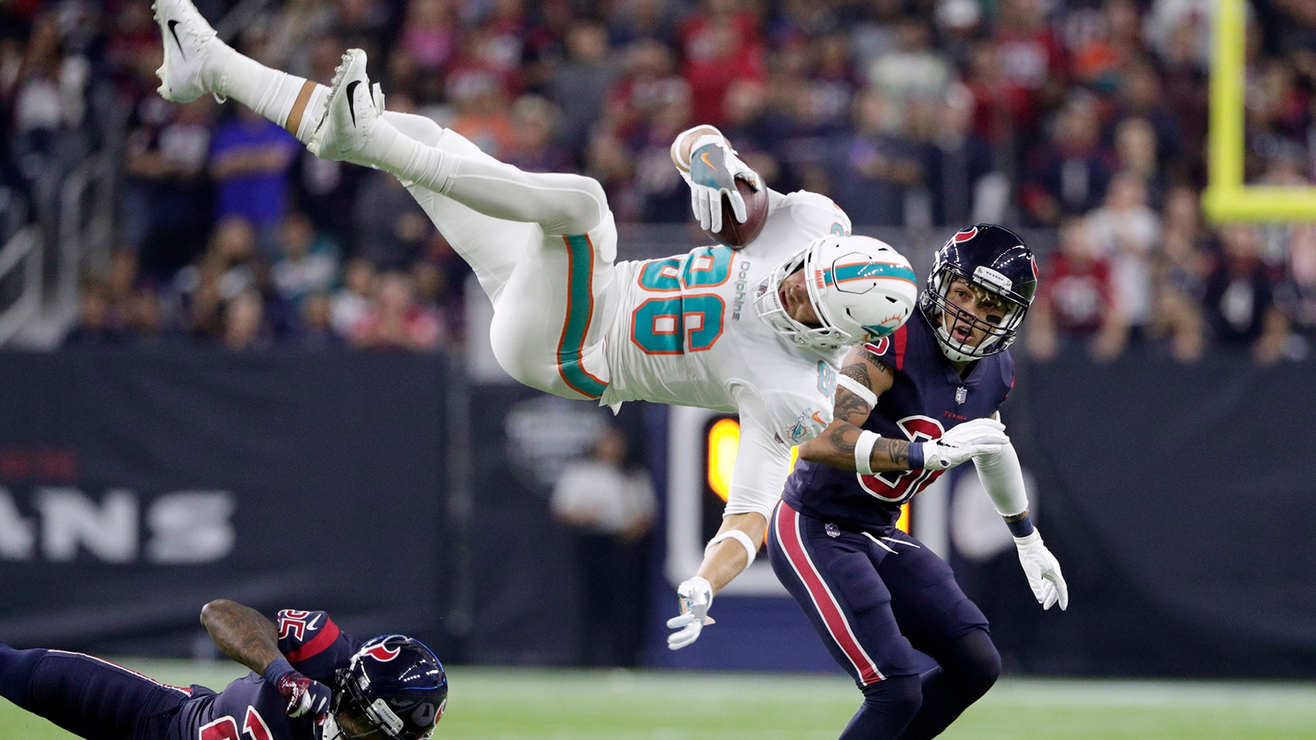 Miami Dolphins Mike Gesicki is upended by Houston Texans Kareem Jackson after a catch as free safety Tyrann Mathieu looks on during the first half of an NFL football game in Houston, Oct. 25, 2018. 