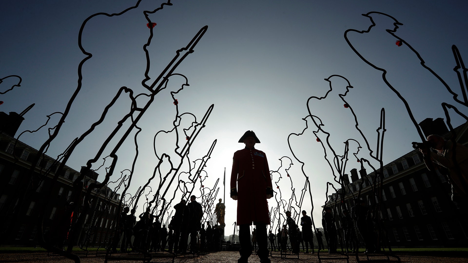 A Chelsea Pensioner, in his ceremonial uniform as a retired member of the British army poses with 6 foot 'Tommy' figures at the Royal Hospital Chelsea in London, Oct. 16, 2018. 