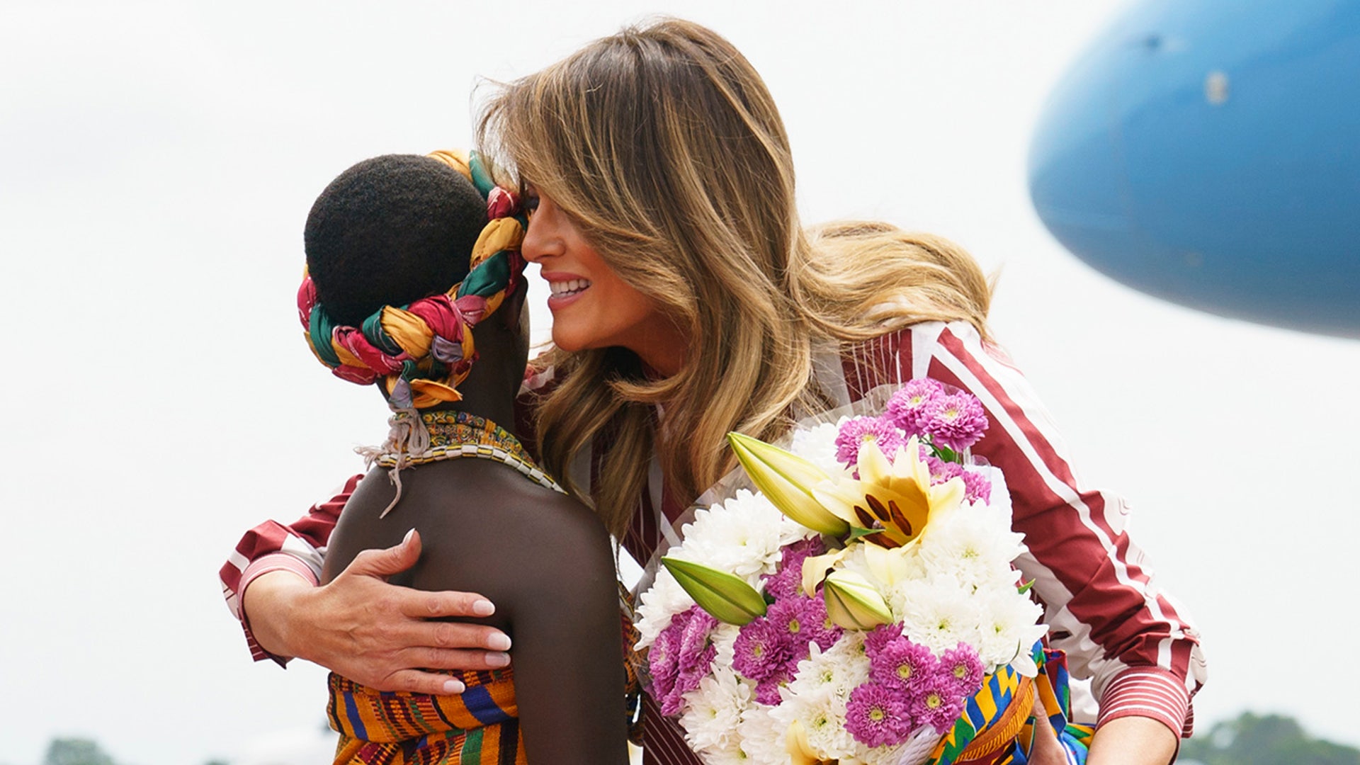 First lady Melania Trump embraces Lillian Naa Adai Sai, 8, as she receives flowers upon arrives at Kotoka International Airport in Accra, Ghana, Tuesday, Oct. 2, 2018. (AP Photo/Carolyn Kaster)