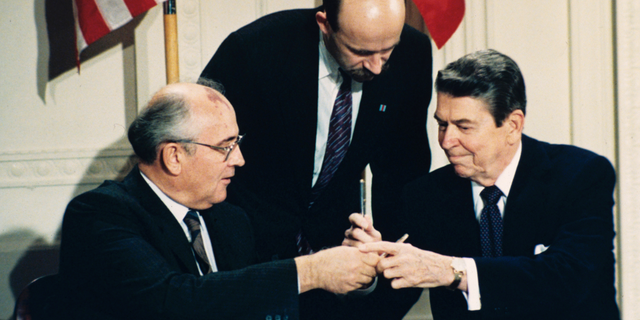 FILE - In this Dec. 8, 1987 file photo U.S. President Ronald Reagan, right, and Soviet leader Mikhail Gorbachev exchange pens during the Intermediate Range Nuclear Forces Treaty signing ceremony in the White House East Room in Washington, D.C. Gorbachev's translator Pavel Palazhchenko stands in the middle. Trump's announcement that the United States would leave the Intermediate-Range Nuclear Forces, or INF, treaty brought sharp criticism on Sunday Oct. 21, 2018, from Russian officials and from former Soviet President Mikhail Gorbachev, who signed the treaty in 1987 with President Ronald Reagan. (AP Photo/Bob Daugherty, File)