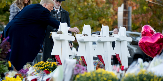 President Donald Trump, accompanied by first lady Melania Trump, left, and Tree of Life Rabbi Jeffrey Myers, right, places a stone from the White House at a memorial for those killed at the Tree of Life Synagogue in Pittsburgh, Tuesday, Oct. 30, 2018. (AP Photo/Andrew Harnik)