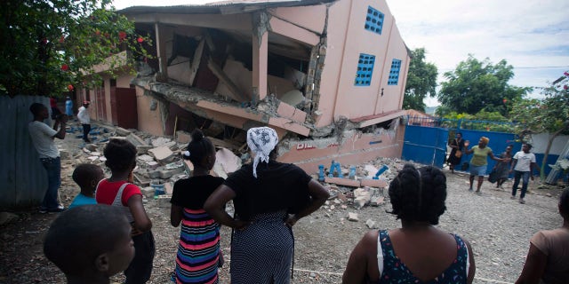 Residents stand looking at a collapsed school damaged by a magnitude 5.9 earthquake the night before, in Gros Morne, Haiti, Sunday, Oct. 7, 2018. Emergency teams worked to provide relief in Haiti on Sunday after the quake killed at least 11 people and left dozens injured. (AP Photo/Dieu Nalio Chery)