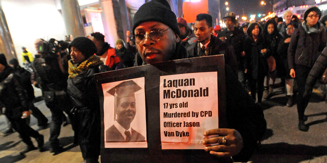 FILE - In this Nov. 24, 2015 file photo, a man holds a sign with a photo of Laquan McDonald on it, during a protest of the police shooting 17-year-old McDonald, in Chicago. The city of Chicago is watching closely for word of a verdict in the case of Chicago police Officer Jason Van Dyke charged with murder in the 2014 shooting of McDonald. The Chicago Police Department has canceled days off and put officers on 12-hour shifts. (AP Photo/Paul Beaty, File)